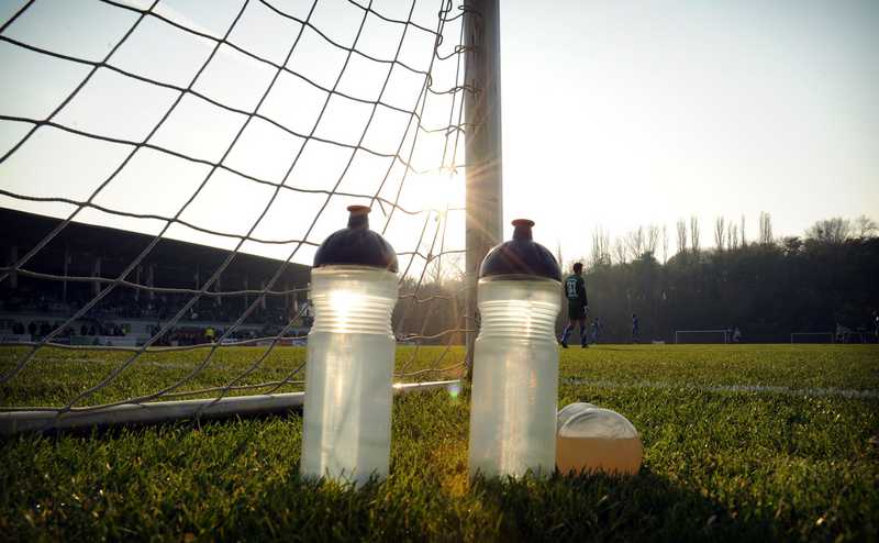 Zwei Trinkflaschen stehen auf dem rasen vor einem Fußballtor.