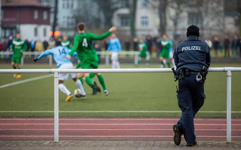 Ein Polizist in Uniform beobachtet ein Fußballspiel